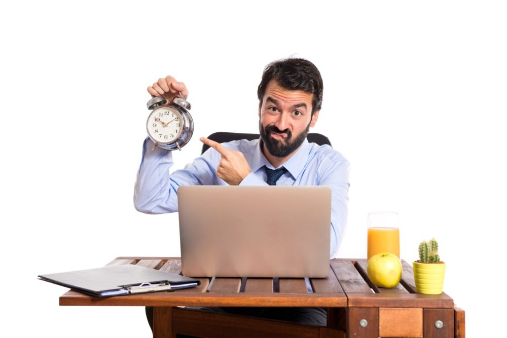 businessman holding a clock to show the pressure before logging off at work