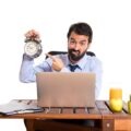 businessman holding a clock to show the pressure before logging off at work