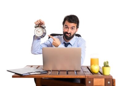 businessman holding a clock to show the pressure before logging off at work