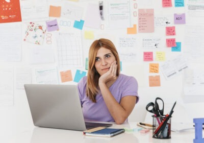 A young woman thinking in front of her laptop with colorful sticky notes, representing the LinkedIn personality in MENA.