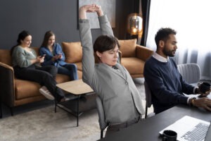 “team stretching at their desks while one person remains steady, reflecting the hidden work hero identity”