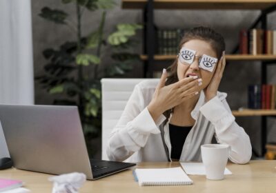 Woman hiding fatigue with sticky notes while yawning after a meeting showing extended meeting recovery time