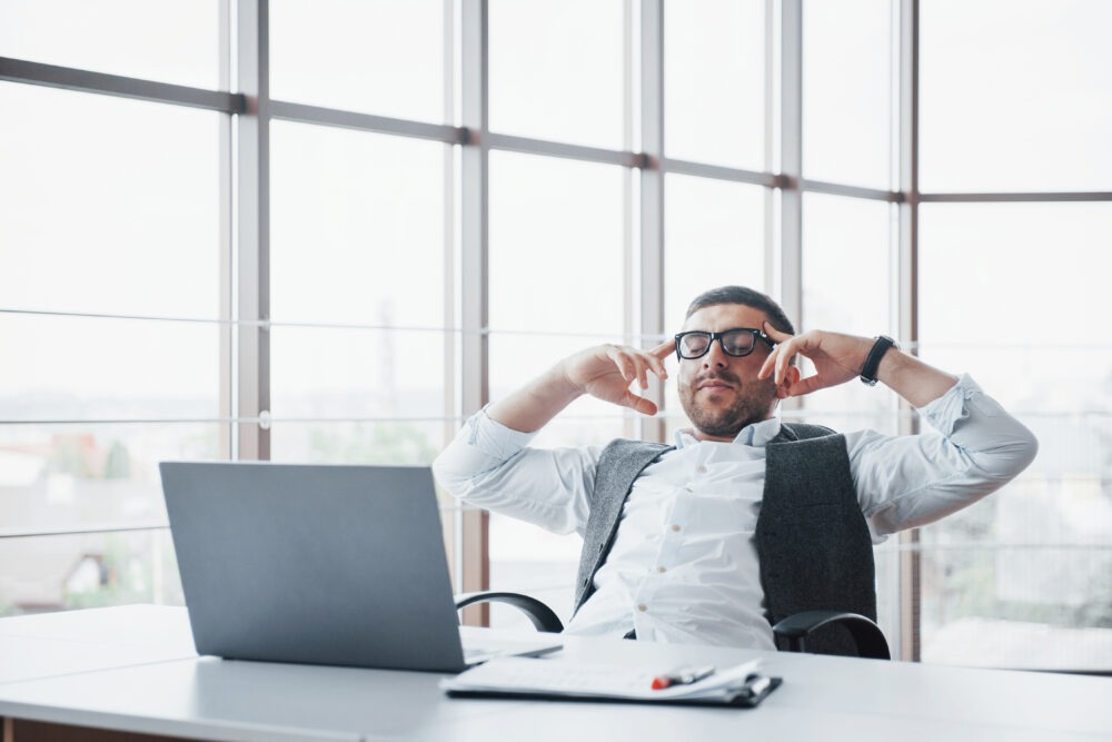 Young man working on a laptop while emotionally detached, representing silent burnout and autopilot at work