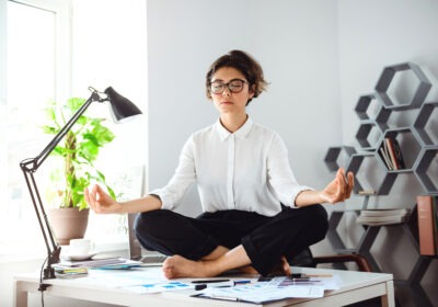 Young businesswoman meditating at her office desk representing work life balance in the Middle East