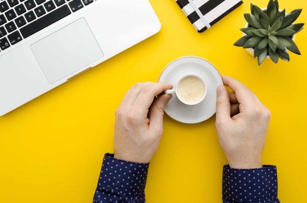 A calm desk with a laptop and a warm coffee mug in morning light, symbolizing micro awakenings at work and the quiet moments that reset attention.