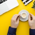 A calm desk with a laptop and a warm coffee mug in morning light, symbolizing micro awakenings at work and the quiet moments that reset attention.