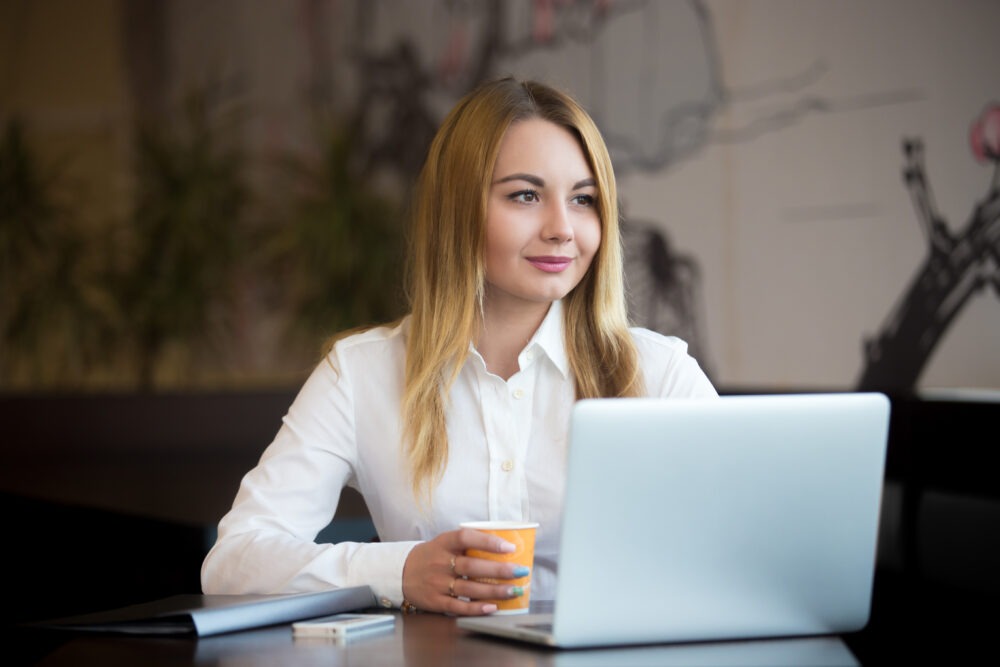 Professional woman smiling while working on her laptop in a calm office setting