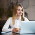Professional woman smiling while working on her laptop in a calm office setting