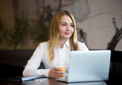 Professional woman smiling while working on her laptop in a calm office setting