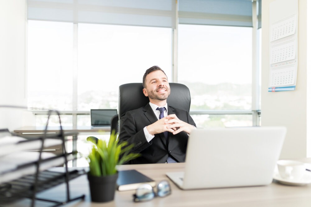 Calm business leader sitting at a desk in a modern office, focused and thoughtful in a quiet work environment