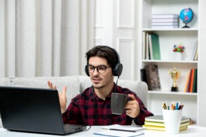 Young professional in a checked shirt and glasses studying online at home